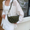 A woman holds a dark green faux suede hobo crossbody bag with gold rivet accents in a white shirt.