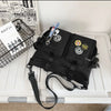 A black nylon crossbody bag with various charms and accessories is displayed next to a wire basket.
