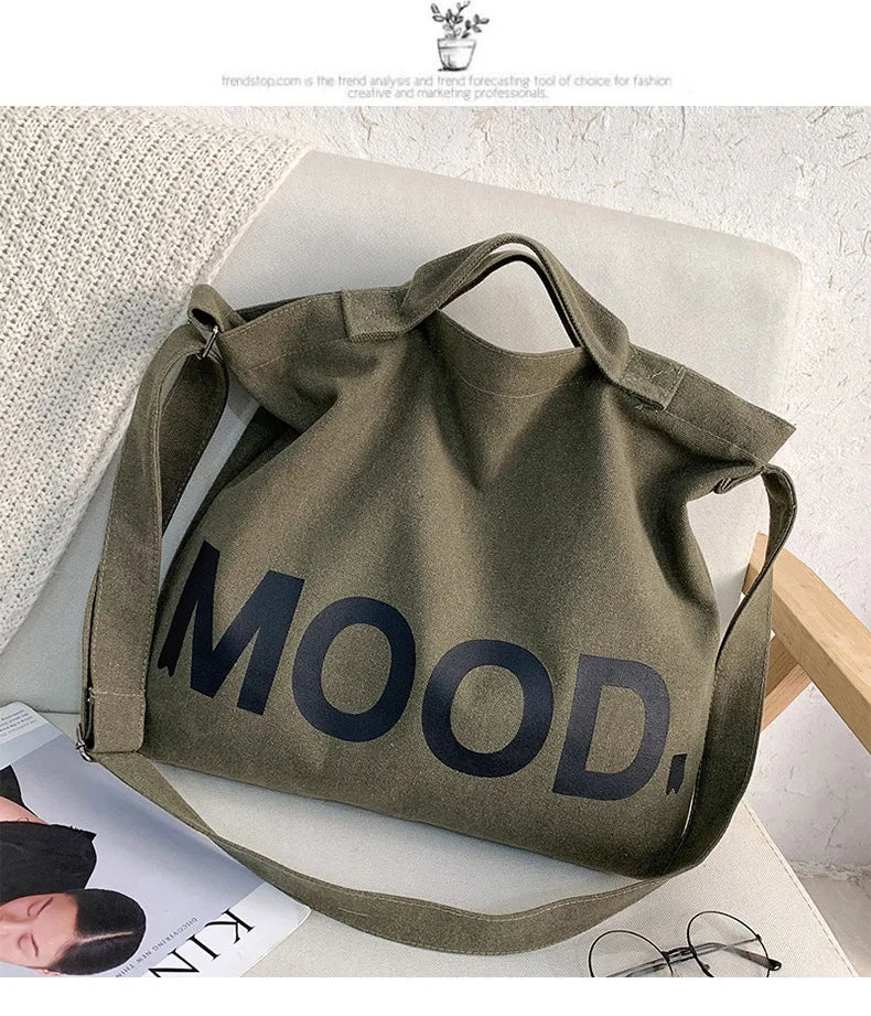 A dark olive canvas tote bag featuring the word MOOD printed in large, dark lettering.
