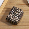 A compact wallet made of leopard print PU leather resting on a wooden surface.