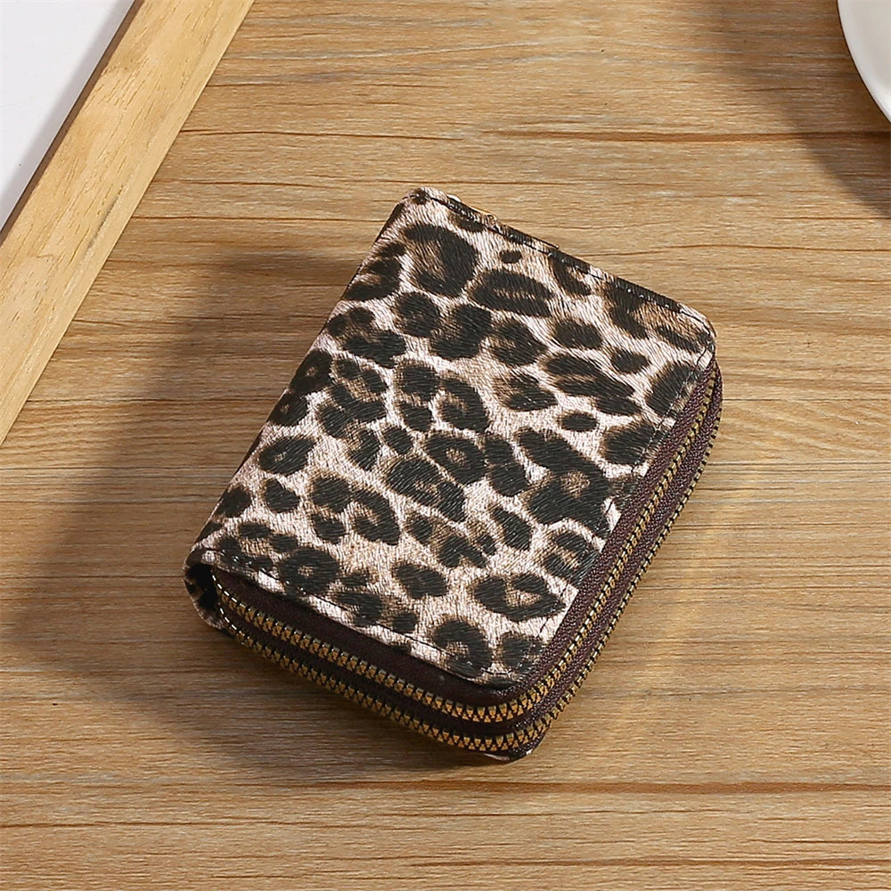 A compact wallet made of leopard print PU leather resting on a wooden surface.