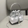 Silver crystal-embellished evening clutch bag with a chain strap resting on a light surface.