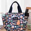 Tote de tela estampada con correa azul oscuro y botella de silicona negra, con ilustraciones de animales del bosque.