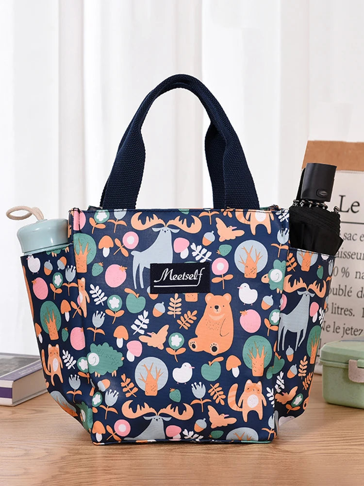 Tote de tela estampada con correa azul oscuro y botella de silicona negra, con ilustraciones de animales del bosque.