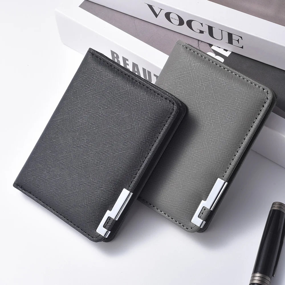 A dark gray slim vertical men's card wallet resting on a white surface next to a magazine.