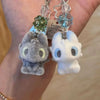 A pair of plush toys resembling Toothless and Hiccup characters are displayed on a keychain.