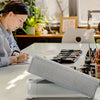 A light gray protective cover for a Cricut Maker device resting on a white table.