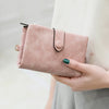 A light pink multi-slot frosted card wallet held by a person, featuring a black pull tab and an emerald green ring finger nai