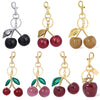 A collection of pink crystal cherry fruit keychains in various colors and finishes.