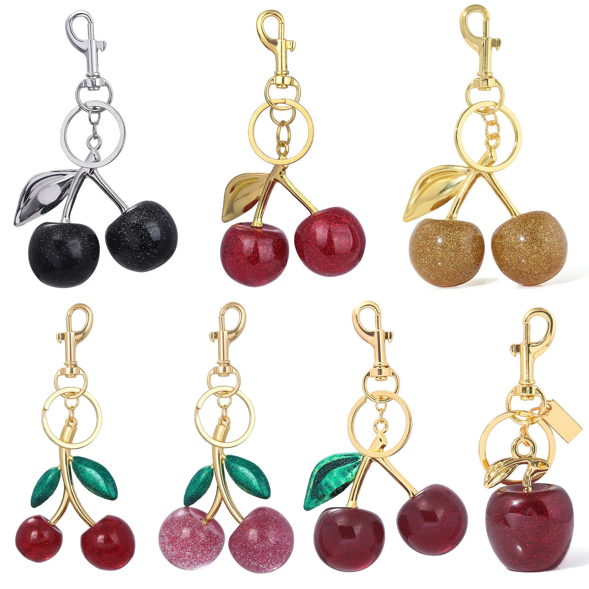 A collection of pink crystal cherry fruit keychains in various colors and finishes.
