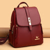 Un sac à dos en cuir microfibre marron vintage bordeaux sur fond beige.