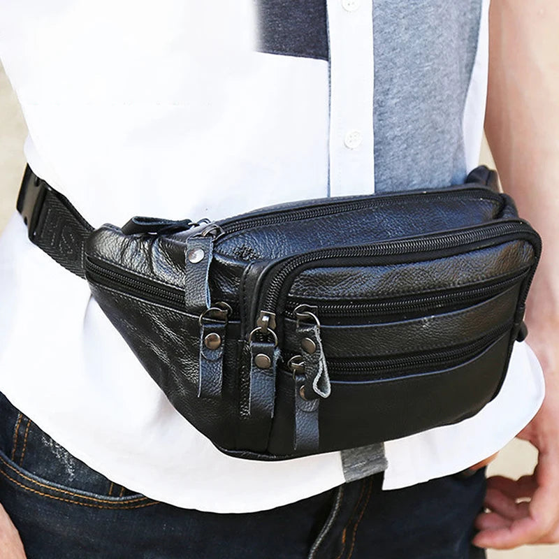 Un sac à taille noire en cuir véritable pour homme, porté par une personne contre une chemise blanche et un pantalon foncé.
