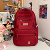 A red backpack with a gray strap and pockets is displayed on a white surface next to various collectibles.