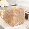 A quilted fabric storage basket with floral pattern and carry handles sitting on a white surface.