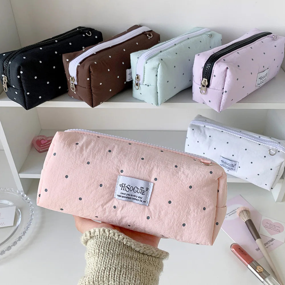 Eine Sammlung von rosa, braun und mintgrünen Polka-Dot-Bleistifthaltern auf einem Regal.
