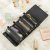A black portable detachable makeup bag is shown open, lined with a fluffy white surface and surrounded by cosmetic products.