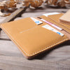 A tan genuine cowhide leather passport and ticket holder with a pink ticket visible on the cover.