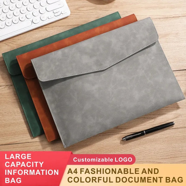 A stack of four customizable leather document bags in shades of green, brown, and gray with a black pen.