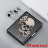 A black slim card holder featuring a skull design and two silver clip-on earrings are displayed on a light gray surface.