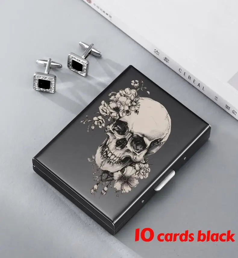 A black slim card holder featuring a skull design and two silver clip-on earrings are displayed on a light gray surface.