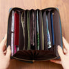 A brown PU leather zipper clutch wallet is open, displaying multiple slots for cards and phones.