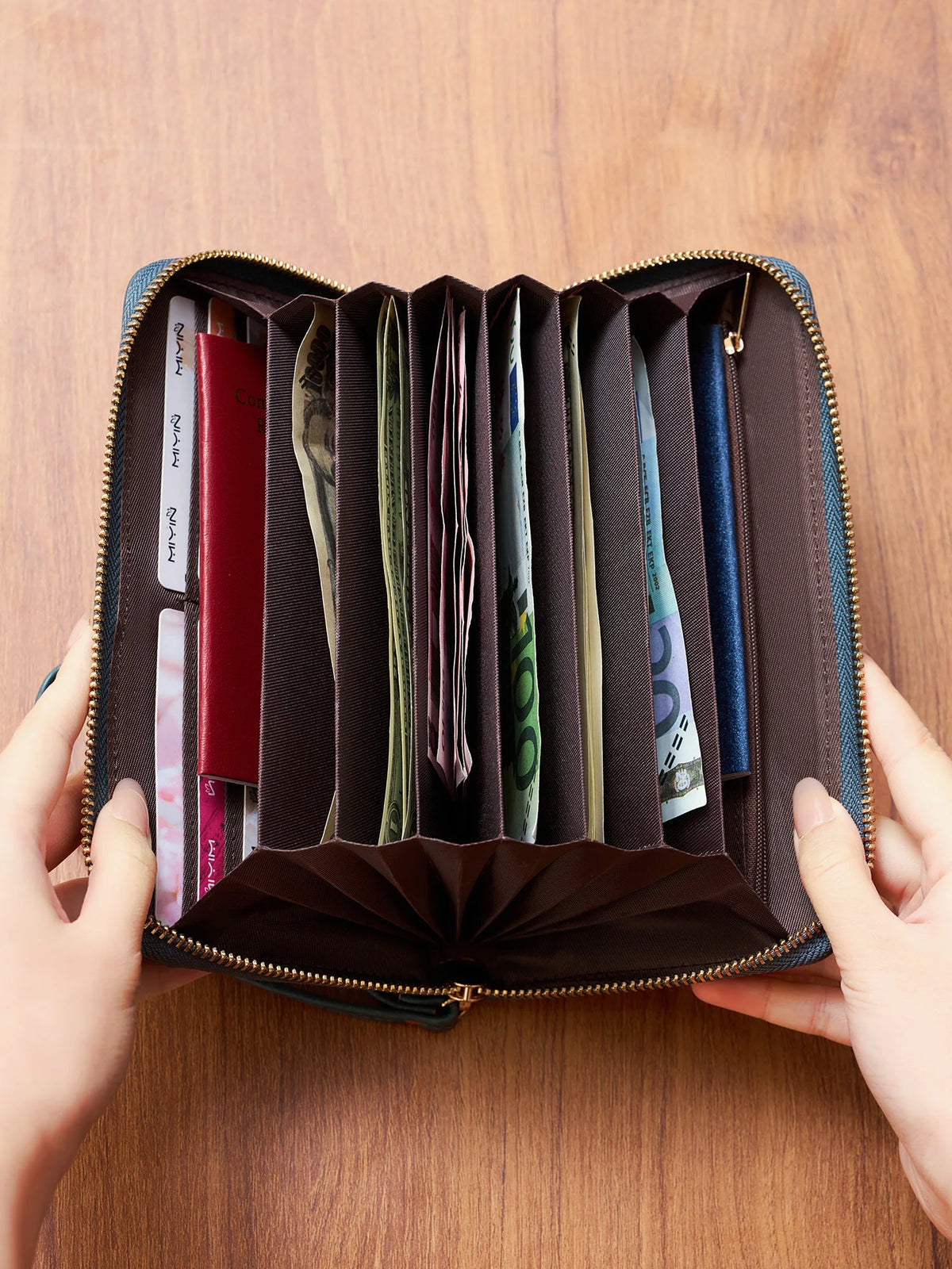 A brown PU leather zipper clutch wallet is open, displaying multiple slots for cards and phones.