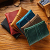 A collection of five minimalist full-grain leather passport holders and card wallets in various earthy tones are arranged on 