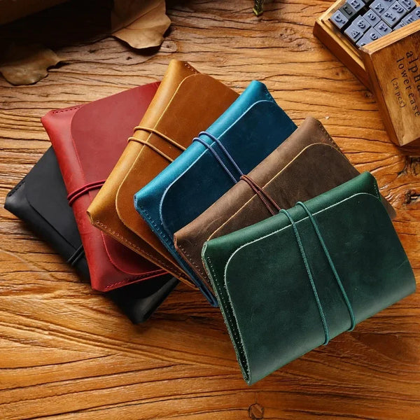 A collection of five minimalist full-grain leather passport holders and card wallets in various earthy tones are arranged on 