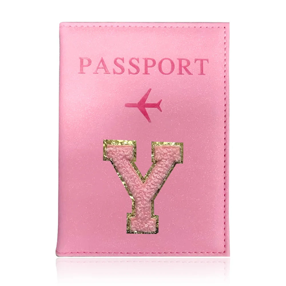 A pink leather passport holder with a gold initial Y embossed on the cover.
