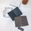 A dark blue geometric print passport wallet next to a white tissue and a minimalist box.