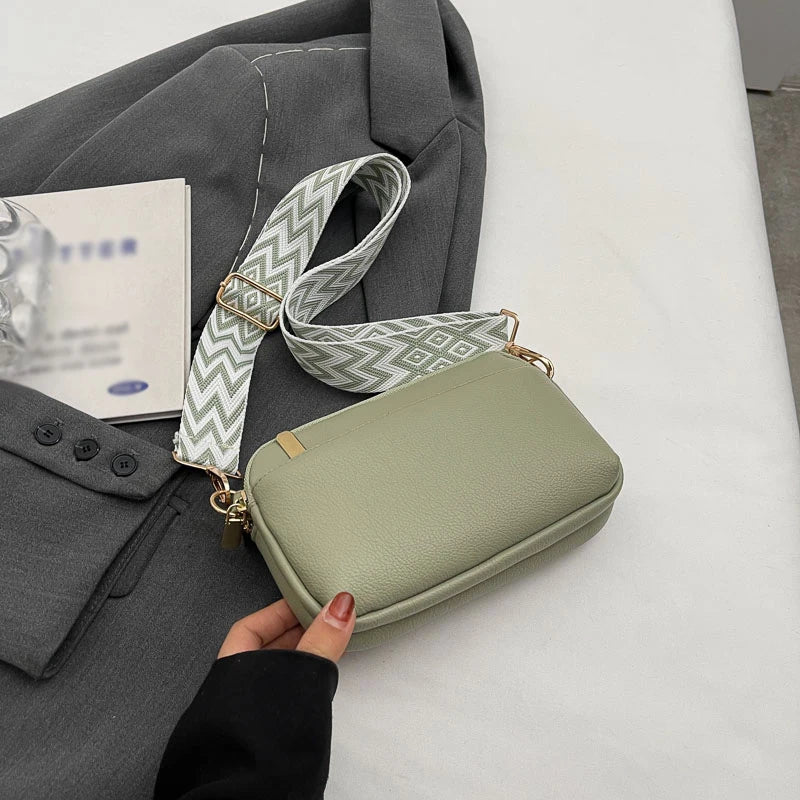 A light green vegan PU crossbody bag with a patterned strap is shown next to a gray blazer.
