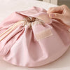 A hand is opening a pink instant-open flat lay makeup organizer bag, showing the interior lining.
