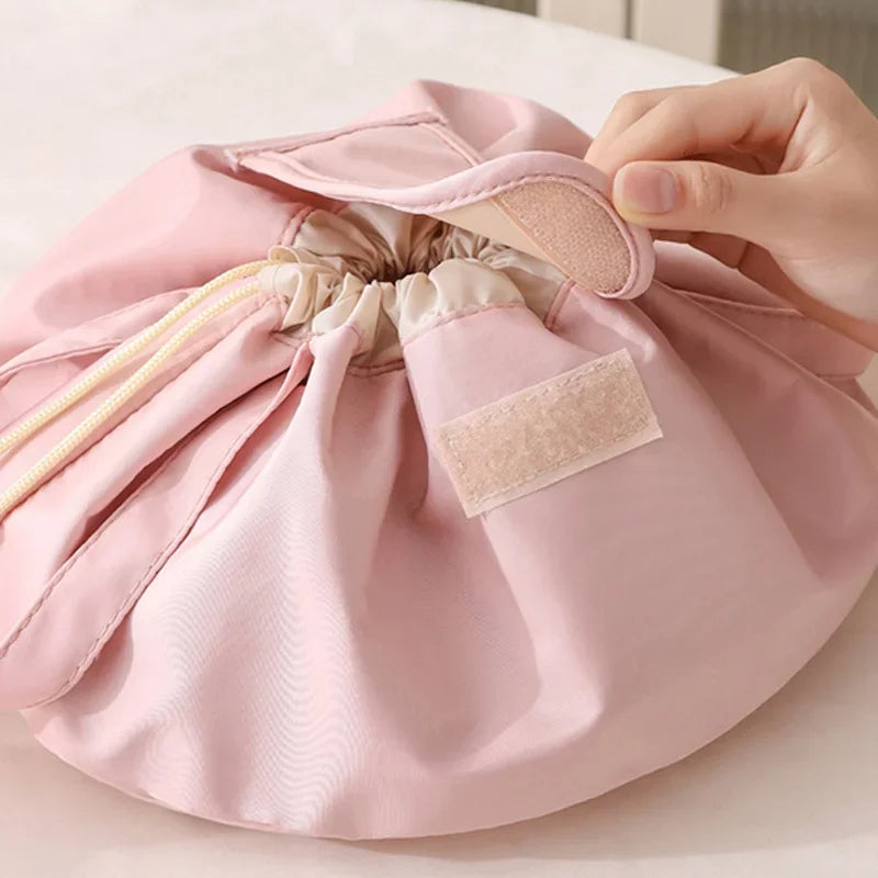 A hand is opening a pink instant-open flat lay makeup organizer bag, showing the interior lining.