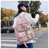 A woman wearing a pink backpack with a padded laptop compartment walks across a crosswalk in an outdoor setting.