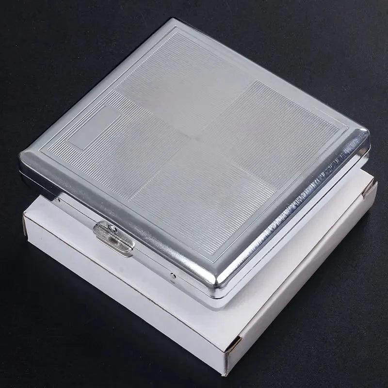 A silver decorative metal cigarette storage box with a clear lid resting on a dark surface.