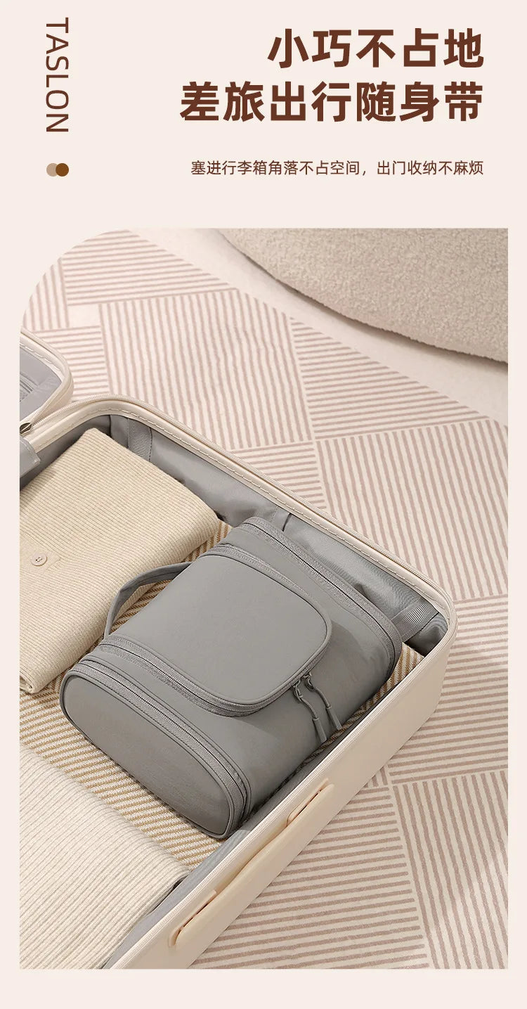 A gray hanging toiletry bag is shown open inside a light-colored box on a patterned surface.