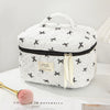 A white quilted makeup bag with black polka dots and a black zipper, featuring a light yellow ribbon.