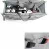 A gray fabric handbag with an interior organizer insert showing various small cosmetic and accessory items.