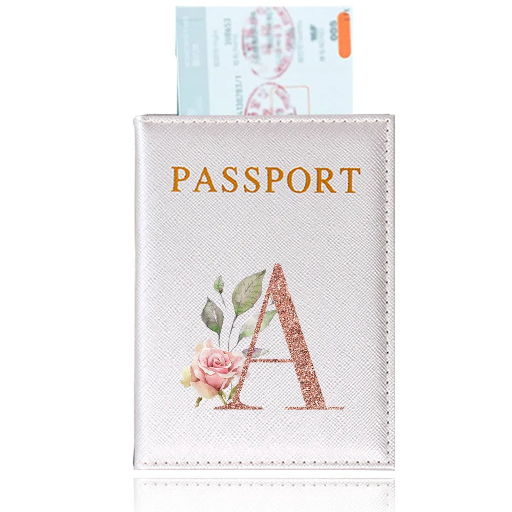 A pink leather passport holder with a gold embossed letter A design and an attached passport.