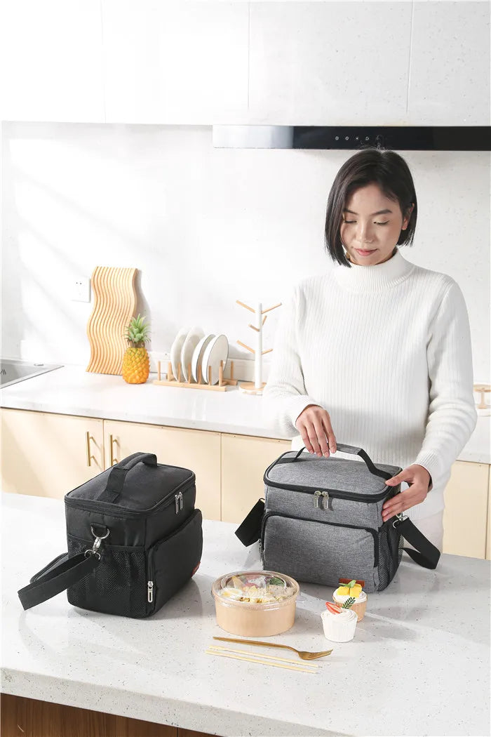 A woman holds a gray insulated thermal lunch bag on a kitchen counter.