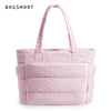 Sac fourre-tout matelassé rose pâle avec poignée sur fond blanc.