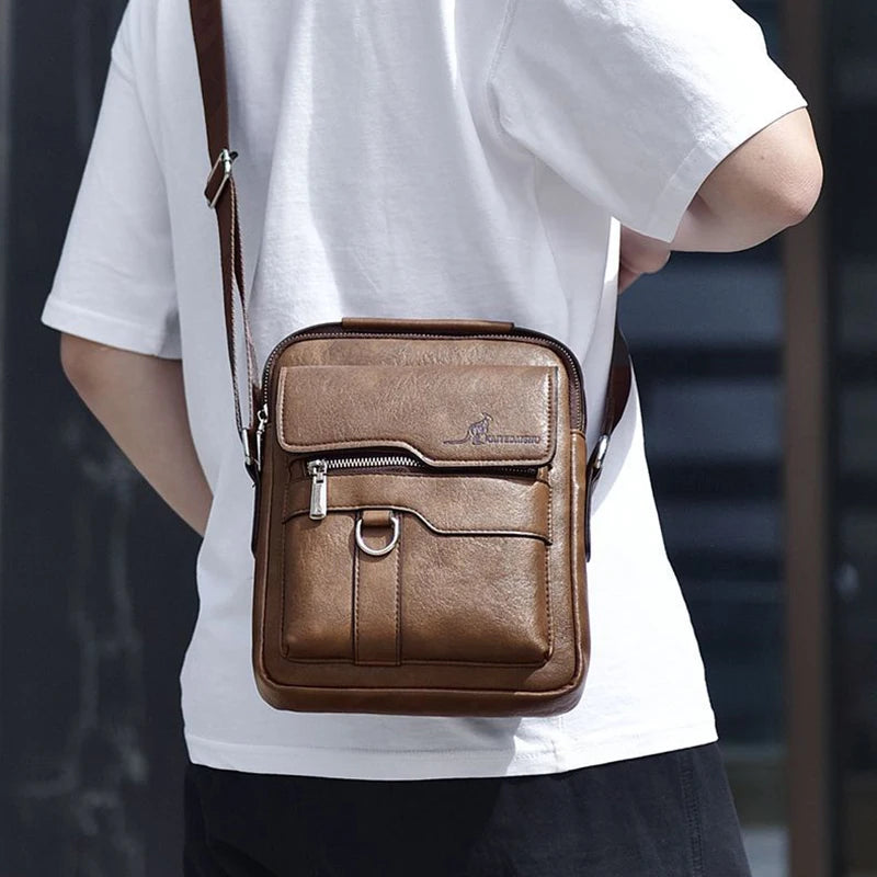 Una vieja bolsa de cuero marrón tipo messenger llevada en el hombro sobre una camiseta blanca.