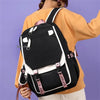 Eine Frau trägt ein schwarz-weißes Leinenschulrucksack-Set über einem orangefarbenen Shirt.