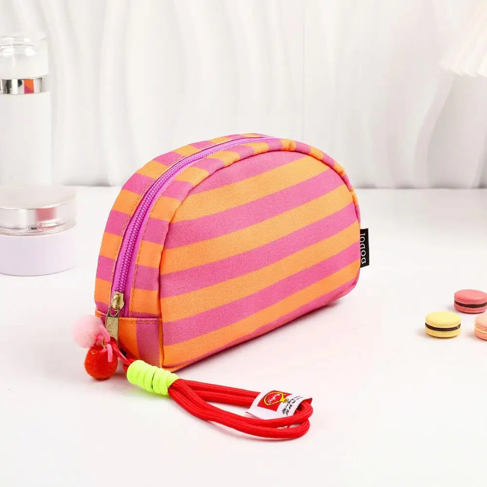 Pochette en crochet rayée rose et orange avec un cordon rouge.
