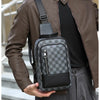 A man wearing a brown leather jacket and dark shirt holds a gray and black geometric pattern crossbody bag.