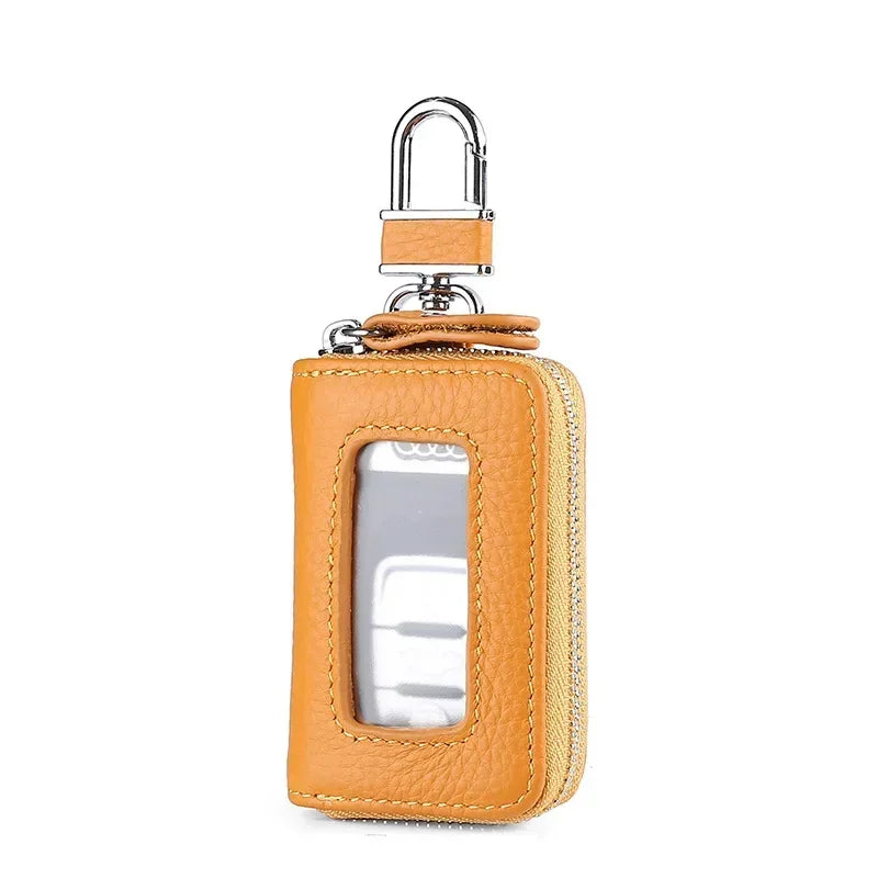 A tan leather car key case with a transparent window and silver clasp.