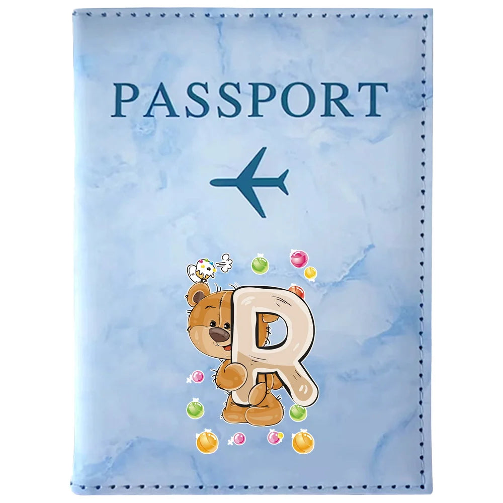 A light blue passport card holder featuring a vintage letter print of the letter R and a small airplane icon.