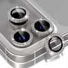 A silver camera lens protector with a glitter diamond lens and metal frame resting on a gray surface.
