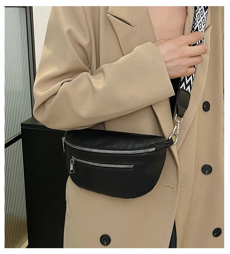 A woman wearing a beige trench coat holds a black PU leather multi-pocket crossbody bag.