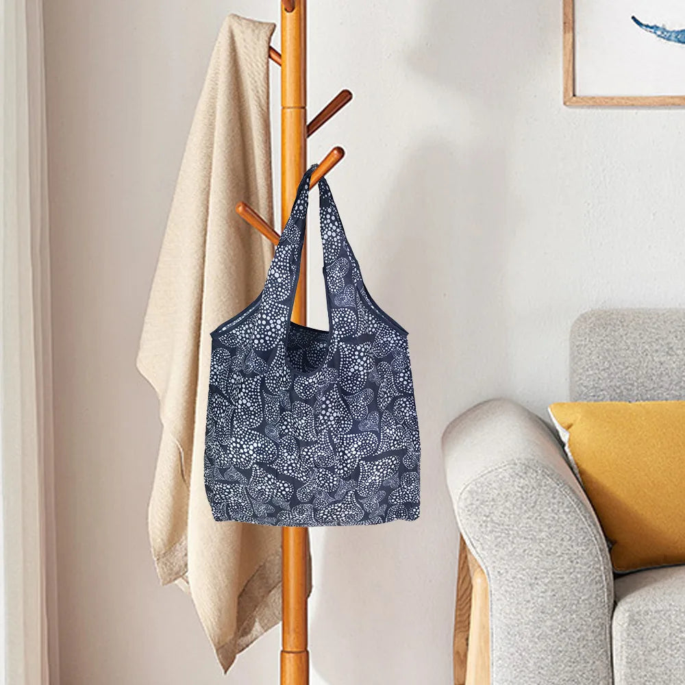 A dark blue patterned reusable eco tote shopping bag hanging on a wooden rack.